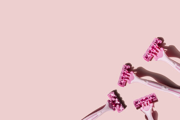 Four pink women's razors on a pink background.