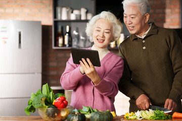Elderly couple using tablets for cooking