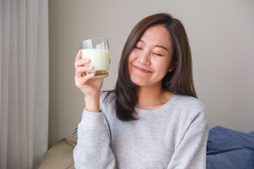 Portrait image of a young woman with closed eyes holding and drinking fresh milk