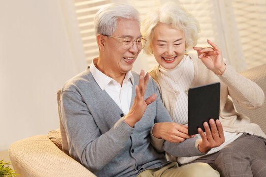 Elderly couple sitting on sofa using tablet