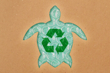 Sea turtle silhouette made of recycled paper with recycling symbol on plastic bubble wrap - Concept of ecology and ocean pollution