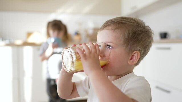 children drinking juice. happy family a healthy eating kid dream concept. daughter son drinking yellow juice from a glass cup in kitchen indoor. child drinking fruit juice. Young team drinking juice