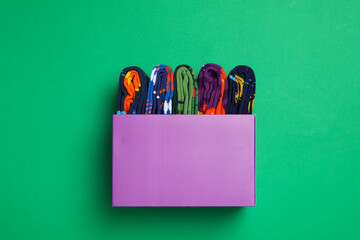 Box with socks on green background, top view
