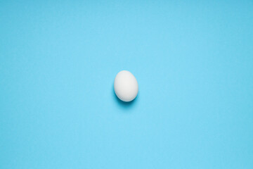 White egg on blue background, space for text