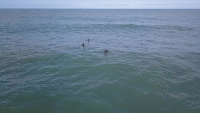 Aerial footage of surfers on their surfboards waiting for the perfect wave at Coxos in Ericeira, Portugal. The beauty of the waves and the surrounding scenery are breathtaking.