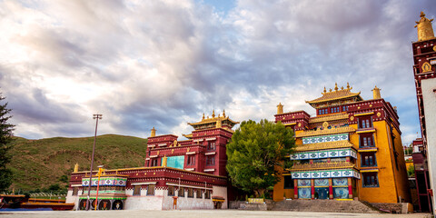 Famous Buddhist Litang Monastery in Litang town in Kham (Eastern Tibet), Sichuan province, China. Panorama with dramatic sunset sky