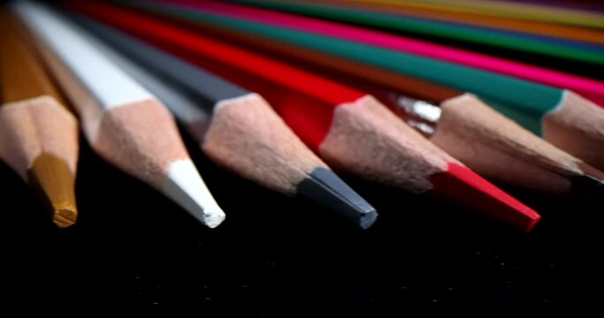 Sharpened pencil tips of different colors on dark background. Stationery product made for children and adults for educational purposes macro