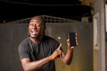 excited African black guy holding a smartphone with white blank screen