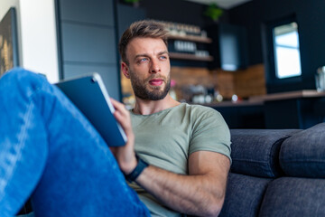Fototapeta premium A graphic designer uses a tablet to create a concept for a new project from the comfort of his living room