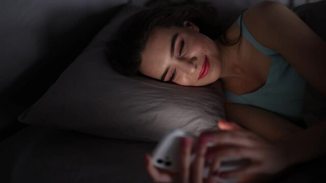 Young woman serf in social network in phone before sleep in her bed
