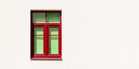 Red window frame on a light background wall facade of the house.
