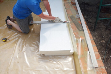 Contractor insulating house foundation floor with rigid foam board insulation with waterproof...