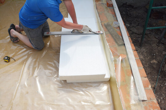 Contractor insulating house foundation floor with rigid foam board insulation with waterproof membrane. Insulated foam sheets for house warm floor foundation.