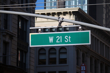 Green big West 21st Street sign hanging on a arch pole in the streets of midtown Manhattan