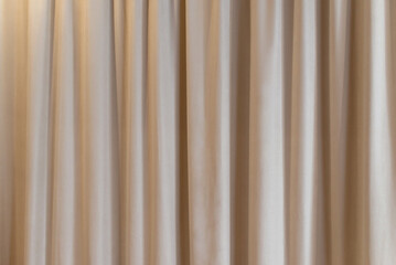 Beige curtain fabric texture and background. Large wall curtain. Curtain for hotel presentations. Cream colored cloth. 