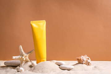 Sunblock, starfish and pebbles on beach sand