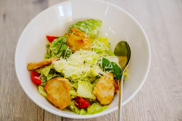 traditional Caesar salad with chicken in a white plate.