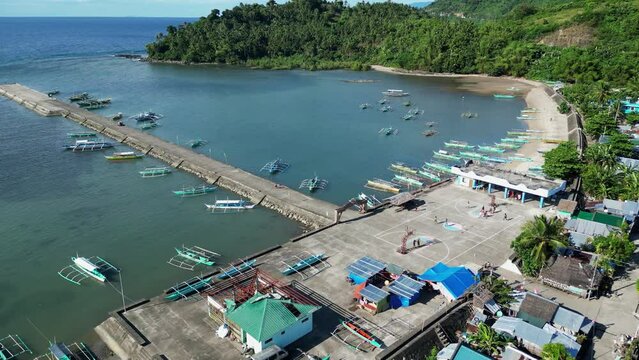 Idyllic Flyover Shot of a Quaint Coastal Village Town facing lagoon and dock with traditional bangka boats anchored. Catanduanes, Philippines.