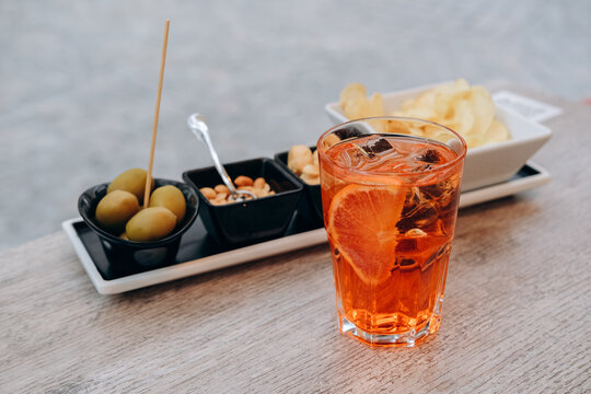 Traditional Italian aperitif cocktail aperol spritz with ice and olives and snaks in Italian bar, an aperitif in Rome, Milan Venice Florence