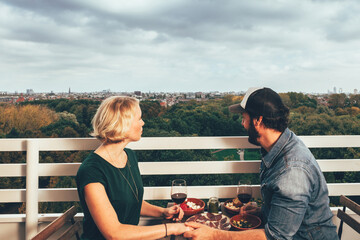 couple enjoys a homemade aperitif together while admiring the city from the terrace on the top...
