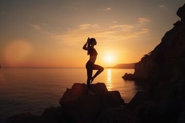 A young woman practicing yoga on a picturesque cliff overlooking the ocean during sunset, the silhouette of her body forming an elegant and balanced pose