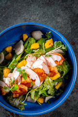 Shrimps salad with arugula, mango and coconut in bowl