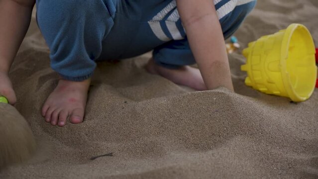 4K, Close-up boy's hand laying on sand, boy used other hand hold sand scoop up sand fill it with other hand, laying on sand boy constantly scooping up sand lonely boy sitting alone.