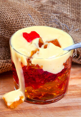 Jelly and custard with spoon and drip on rustic table with burlap cloth