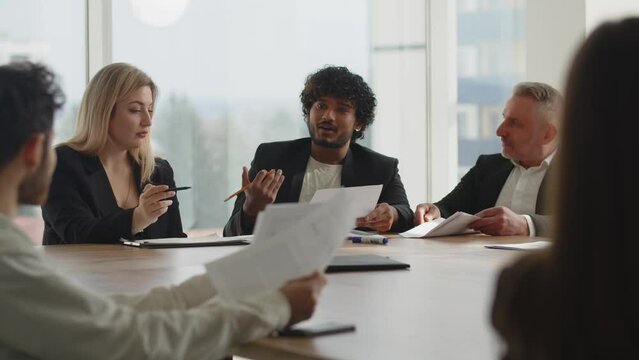 People in business suits holding a meeting of the board of directors in the conference room. A young Indian businessman tells his business partners about the need to restructure the business processes