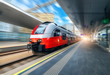 Fototapeta na wymiar Red high speed train in motion on the railway station at sunset. Fast modern intercity train and blurred background. Railway platform. Railroad in Austria. Commercial and passenger transportation 