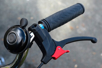 Part of a bicycle handlebar with handbrake and bell. Close up.