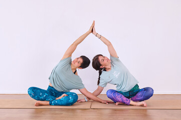 Two girls doing yoga, joining their hands to produce the Anjali mudra