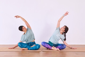 Two girls doing yoga, with their hands apart, making the Chin mudra