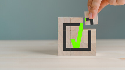 Hand placing wooden cube with green checkmark icon. Goals achievement and business success. Quality...