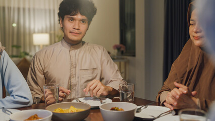 Close-up Happy Asia muslim wife talk to husband Ramadan dinner together at home. Family of two generation catering celebration end of Eid al-Fitr togetherness at home. Hari Raya family reunion.