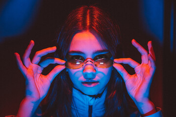 stylized portrait of a young girl with modern glasses using 2 sources of colored light