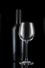 A bottle of wine and a wine glass in front of a black background
