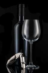 A bottle of wine and a wine glass with an elegant wine set in front of a black background