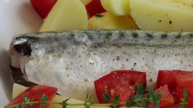 poisson (maquereau) avec pommes de terre, tomate, thym et oignons dans un plat	