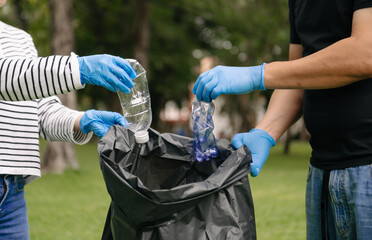 Woman's hand picks up plastic waste for cleaning into recycle bag for cleaningat the park....