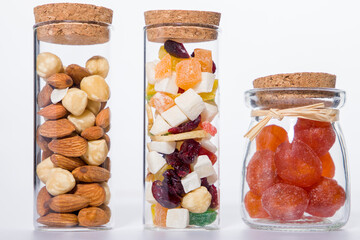 different types of dried fruit and nuts in glass jar, on white background