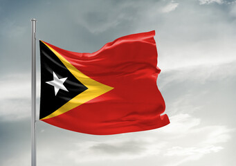 East Timor (Timor-Leste) national flag cloth fabric waving on beautiful sky Background.