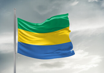 Gabon national flag cloth fabric waving on beautiful sky Background.