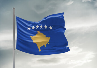 Kosovo national flag cloth fabric waving on beautiful sky Background.