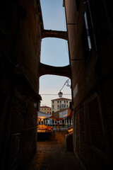 Vertical shot from a narrow alley with the view of a Venice market in the evening