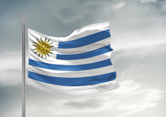 Fototapeta premium Uruguay national flag cloth fabric waving on beautiful sky Background.