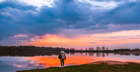 Travel. A woman stands on the lake at sunset. Conscious travel, hiking, self-care, harmony