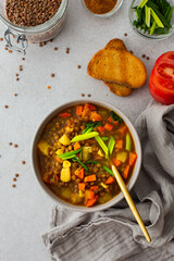 Healthy vegetarian lunches, brown lentil soup with tomatoes and carrots, green onions, potatoes and curry spices, toasted croutons, top view