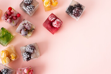 Frozen ice cubes with various fruits, blackberries and raspberries, gooseberries and currants, blueberries and mint, top view