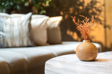 A cozy styled wooden flower pot with dry plant is placed on marble table with background of luxury...